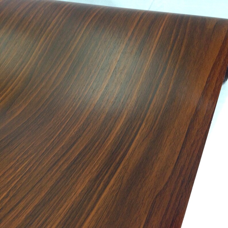 May include: A close-up of a brown woodgrain contact paper roll. The paper has a realistic woodgrain pattern.