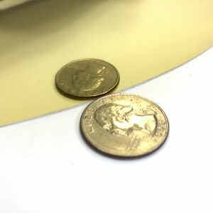 以下が含まれることがあります： 黄色の表面に、2枚のアメリカの25セント硬貨が重ねられています。上の硬貨は少しぼやけています。