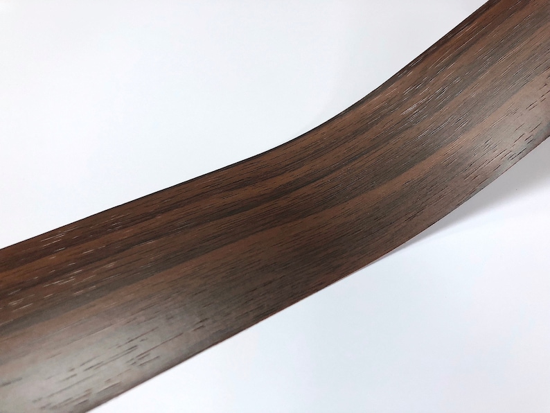May include: A close-up of a dark brown woodgrain vinyl contact paper. The paper has a realistic woodgrain pattern.