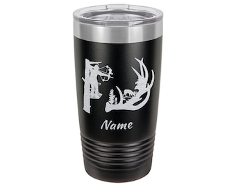 Puede incluir: Un vaso de acero inoxidable negro con una silueta blanca de un cazador con arco y flecha en una plataforma de árbol, una cornamenta de ciervo y la palabra "Nombre" en el lateral.