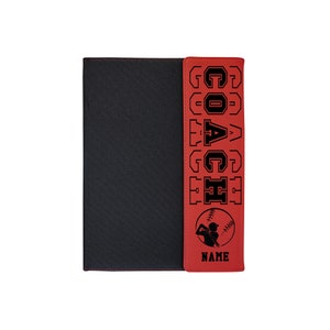 May include: Red leatherette folder with a black cover and a black and white baseball player graphic. The folder has the word "COACH" written vertically in black on the red side.