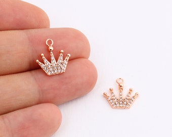 May include: Two gold-tone crown charms with clear rhinestone accents. The charms have a loop at the top for attaching to jewelry.