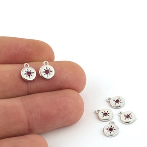 May include: Five silver charms with a pink star in the center. The charms have a loop at the top for attaching to a necklace or bracelet.
