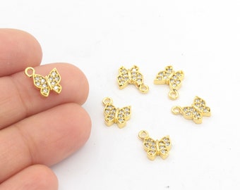 May include: Six gold butterfly charms with clear crystal embellishments. The charms have a loop at the top for attaching to jewelry.