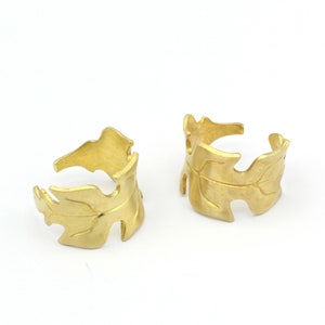 Pode incluir: Dois anéis de ouro em forma de folha. Os anéis são abertos e têm uma superfície texturizada.