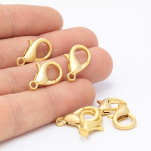 May include: Five gold-toned lobster clasps, a type of fastener used in jewelry making.
