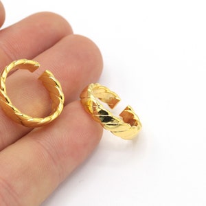 May include: Two gold-toned adjustable rings with a braided design. The rings are open on one side and can be adjusted to fit different finger sizes.