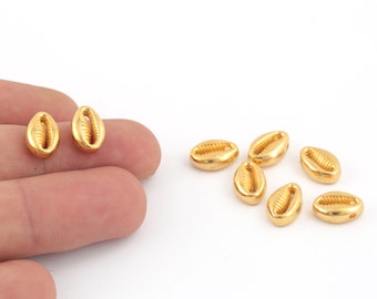 May include: A group of eight gold-colored seashell beads. The beads are oval-shaped and have a detailed texture.