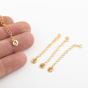May include: Four gold chains with small round charms attached to the ends. The charms are engraved with the letters D, S, H, and E.