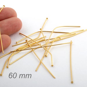 Puede incluir: Un montón de alfileres de cabeza dorados de 60 mm. Los alfileres están ligeramente doblados.