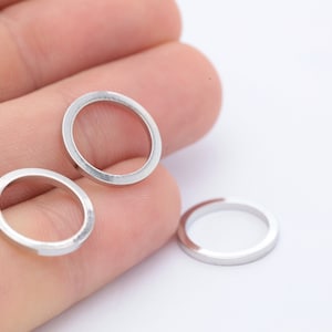 May include: Three silver-toned metal rings, each with a smooth, rounded edge. The rings are arranged on a hand, with two rings on one finger and one ring on another finger.