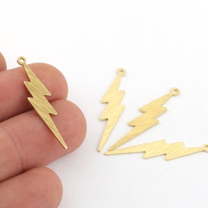 May include: Four gold-colored metal lightning bolt charms with a hole at the top for attaching to jewelry or other crafts.