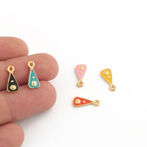 May include: Five gold-tone metal charms with enamel accents. The charms are shaped like teardrops and have two gold dots on each. The charms are in the colors black, teal, pink, yellow, and red.