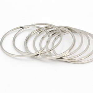 以下が含まれることがあります： 銀色のバングルブレスレット8個セット。ブレスレットは重ねて重ねて、レイヤードルックになっています。