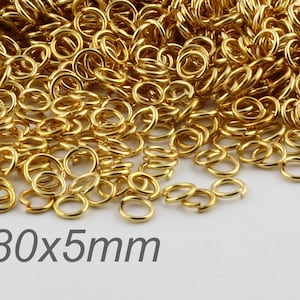 May include: A large pile of gold jump rings, measuring 0.80x5mm. The rings are small and delicate, perfect for jewelry making.