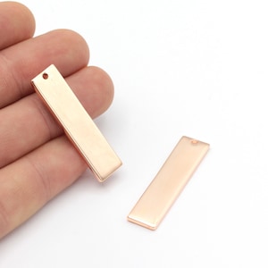 May include: Two gold-colored metal rectangular tags with a hole at the top. The tags are blank and ready for personalization.