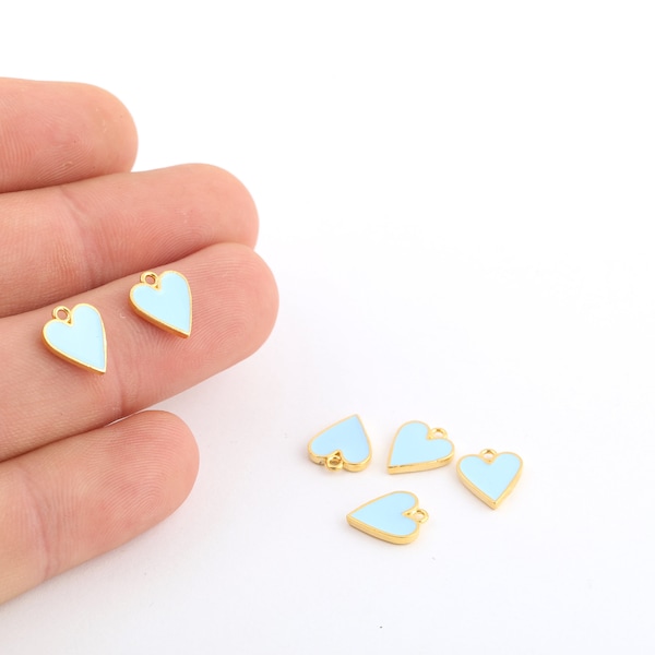 May include: A set of six gold-toned heart-shaped charms with a light blue enamel finish. The charms have a small loop at the top for attaching to jewelry or other crafts.