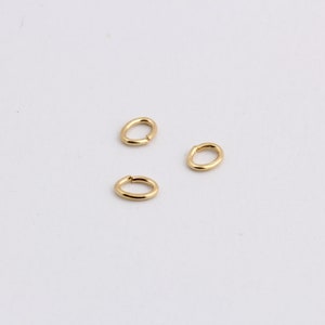 May include: Three gold jump rings, each with a smooth, oval shape.