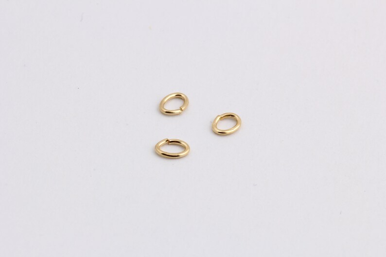 May include: Three gold jump rings, each with a smooth, oval shape.