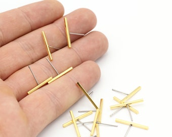 Può includere: Primo piano di una mano che tiene un set di orecchini a barra d'oro. Gli orecchini sono semplici e minimalisti, con un design a barra dritta. Gli orecchini sono perfetti per l'uso quotidiano.