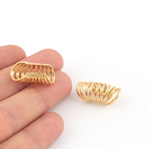 May include: Two gold-colored spiral ear cuffs. The cuffs are made of multiple thin metal rings that are coiled together.
