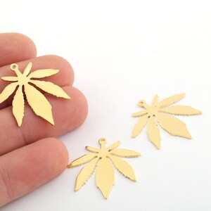 Puede incluir: Tres abalorios de hoja de cannabis de metal de color dorado. Los abalorios son detallados y tienen un agujero en la parte superior para sujetarlos a joyas u otras manualidades.