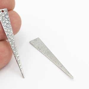 May include: Two silver metal triangle shaped pendant charms with a hammered texture. Each charm has a hole at the top for attaching to jewelry.