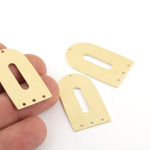 May include: Three gold-colored metal arch shapes with a rectangular hole in the center. Each arch has four small holes around the edge.