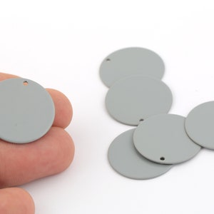 Pode incluir: Seis círculos de metal cinza com um pequeno furo no centro. Os círculos têm um diâmetro de aproximadamente 2,5 cm.