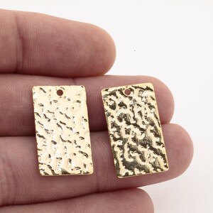 May include: Two gold-colored metal rectangular tags with a hammered texture and a hole at the top.