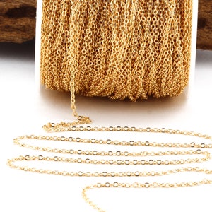 Könnte beinhalten: Eine Spule mit goldfarbener Kette, die Kette liegt auf einer weißen Oberfläche in einer geraden Linie.