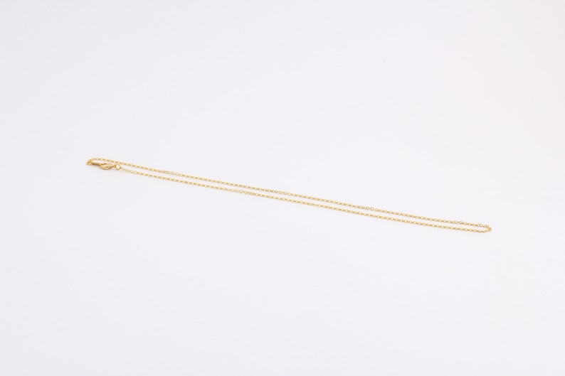 K&ouml;nnte beinhalten: Eine goldene Kettenkette mit einem Karabinerverschluss.