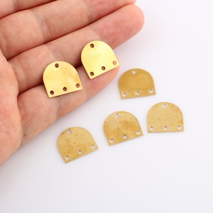 May include: Six gold-colored metal shoe repair patches with four holes each. The patches are arranged in a semi-circle on a white surface.