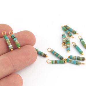 May include: A set of turquoise and gold bead charms with a loop at the top. The charms are made of small, square beads in shades of turquoise and green, with gold accents.