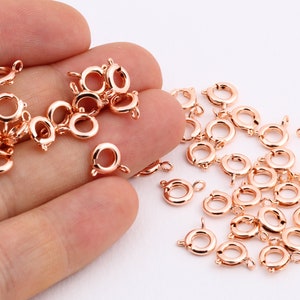 Può includere: Primo piano di un mucchio di chiusure a moschettone in oro rosa, un tipo di componente per gioielli utilizzato per realizzare collane, braccialetti e altri gioielli.
