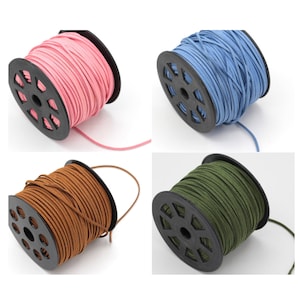 May include: Four spools of suede cord in different colors: pink, blue, brown, and green. Each spool is wound with cord and has a black plastic center.