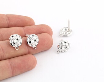 May include: Silver-colored stud earrings with a textured, spherical design. The earrings have a small loop at the bottom and a post for insertion. The image shows multiple earrings against a white background, highlighting the jewelry's details.