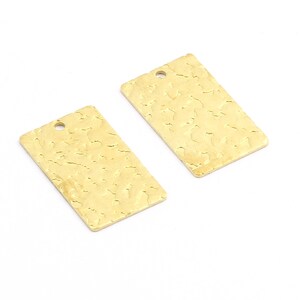May include: Two gold-colored metal rectangular tags with a textured surface and a hole at the top for hanging.