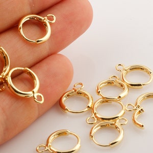 May include: Gold-toned earring hoops with a jump ring for attaching charms or pendants. The hoops are approximately 1 inch in diameter.