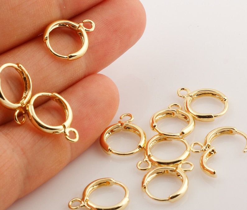 May include: Gold-toned earring hoops with a jump ring for attaching charms or pendants. The hoops are approximately 1 inch in diameter.