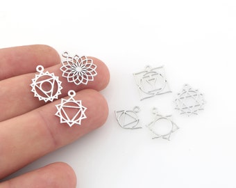 May include: A set of seven silver metal charms featuring different chakra symbols. The charms are in the shape of a circle, square, and star. The charms are perfect for jewelry making or adding a touch of spirituality to your crafts.