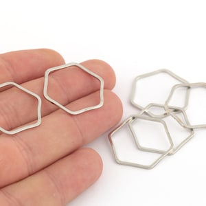 Peut inclure: Un ensemble de six anneaux de saut hexagonaux de couleur argentée. Les anneaux sont tous de la même taille et sont disposés en un tas lâche.