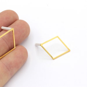 Pode incluir: Um par de brincos quadrados dourados com um design geométrico simples.