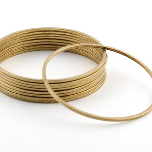 May include: A stack of 10 gold-colored metal rings, with one ring laying on top of the stack.