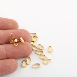 Puede incluir: Primer plano de un montón de baúles de colgantes de metal dorado. Los baúles son pequeños y delicados, y son perfectos para agregar un toque de elegancia a cualquier proyecto de joyería.