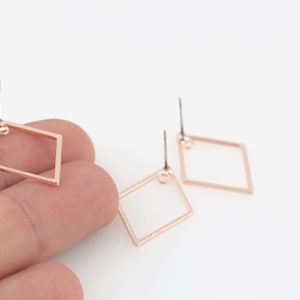 Pode incluir: Um par de brincos quadrados de ouro rosa com um design simples.