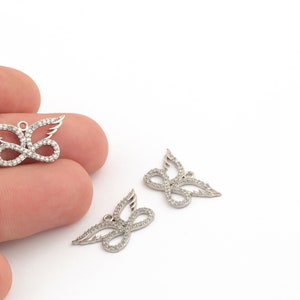 May include: Two silver butterfly charms with clear crystal accents. The charms are on a white background.