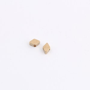 May include: Two gold-colored diamond-shaped beads with a hole in the center.