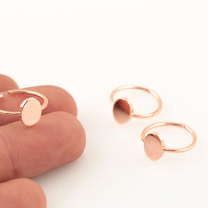 Può includere: Tre orecchini a cerchio dorati con un ciondolo rotondo piatto attaccato a ogni cerchio.