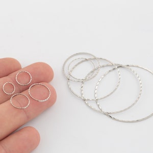 May include: A set of silver jump rings in various sizes. The rings are smooth and have a slightly textured finish.
